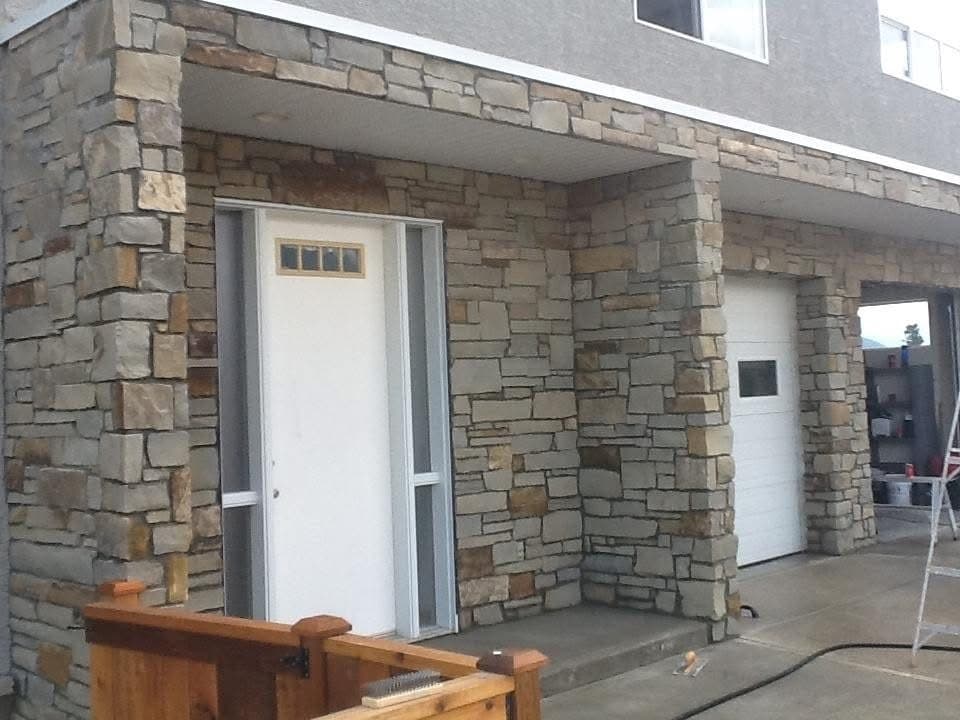 A stacked-stone entrance and garage surround built by First Class Stucco & Masonry